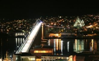 Мост в Тромсё ночью подсвечивается.