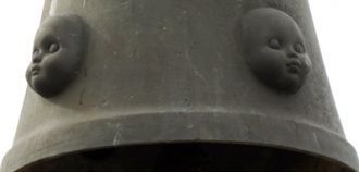 К основанию креста прикреплен колокол, в