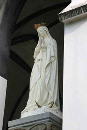 У входа в церковь установлена статуя Дев