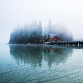Окутанный туманом домик на берегу озера 